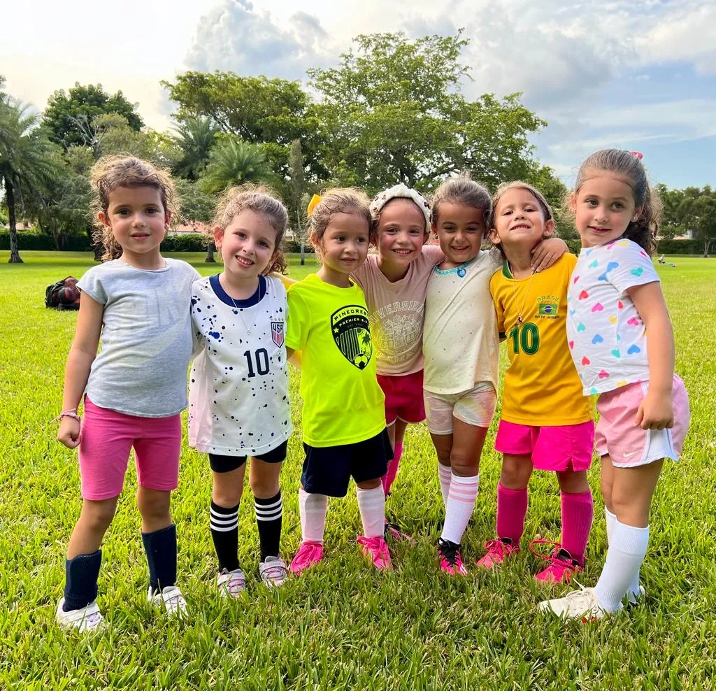 Coach giving high-five to happy soccer kids at KidsPro Academy Miami